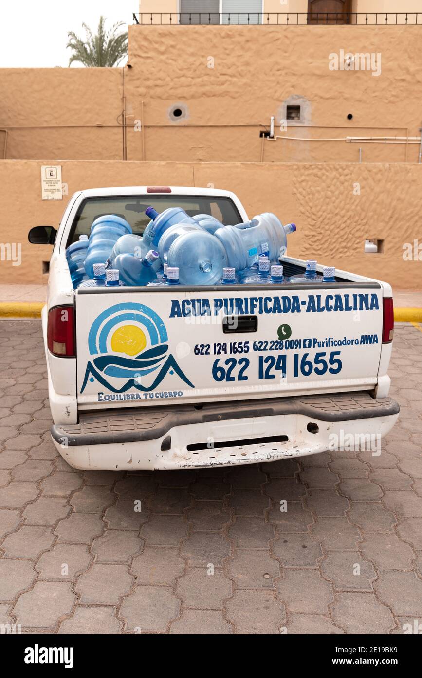 A white truck filled with large blue purified water bottles is parked while making deliveries in San Carlos, Sonora, Mexico. Stock Photo