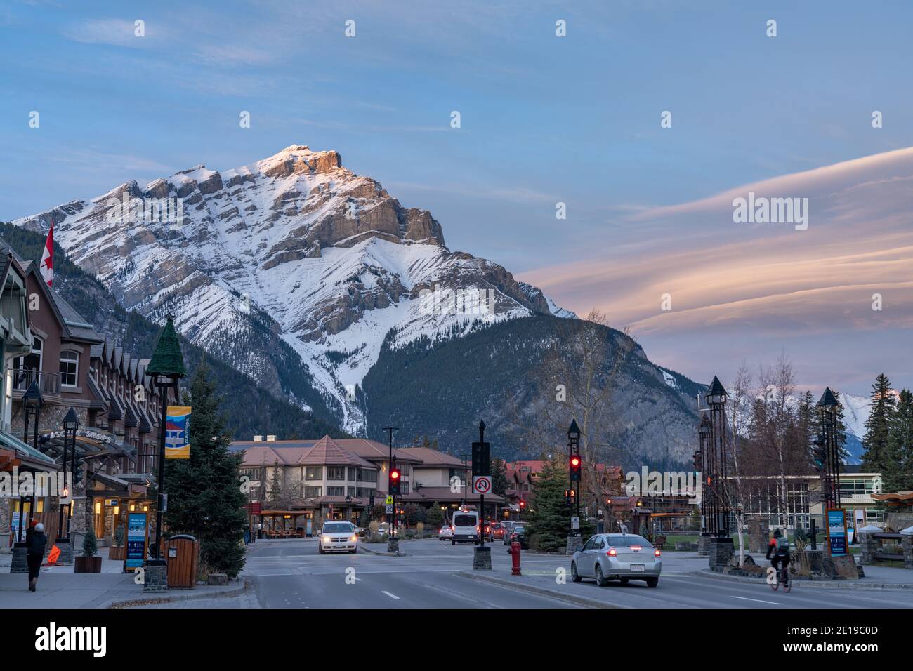 Street view of Banff Avenue in autumn evening. Snow capped Cascade Mountain with pink rosy sky in the background. Stock Photo