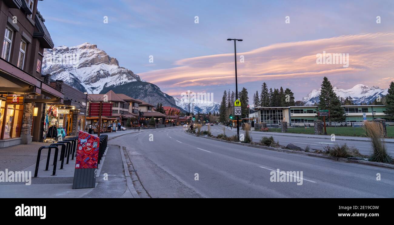 Street view of Banff Avenue in autumn evening. Snow capped Cascade Mountain with pink rosy sky in the background. Stock Photo