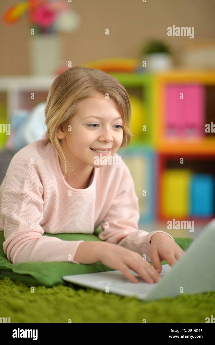 Emotional cute girl using laptop while lying on floor Stock Photo - Alamy