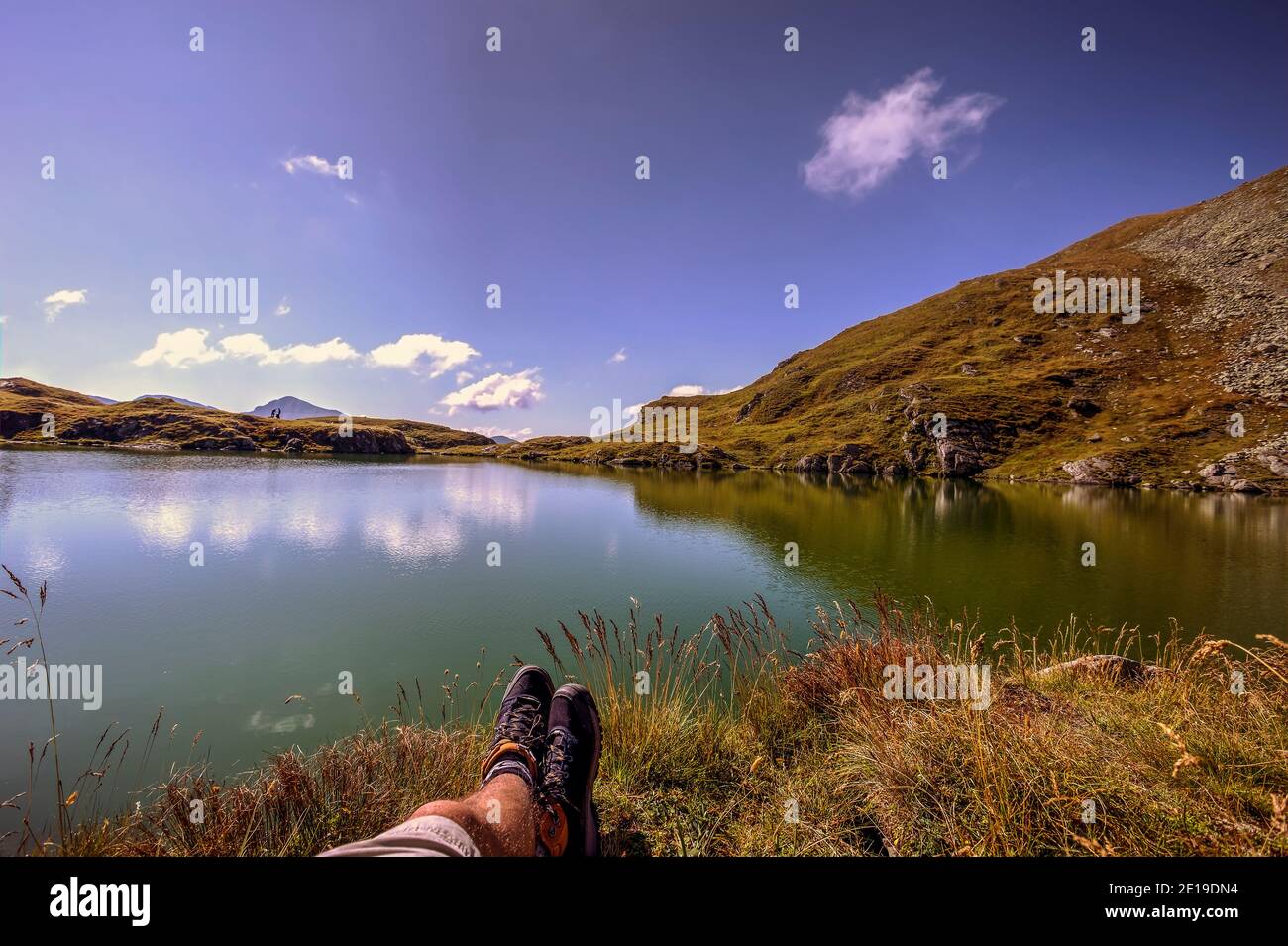 Hiker feet relaxing on the alpine Capra lake, high in the Fagaras massive of the Carpathian Mountains. Photo taken on 31st of August 2019, Sibiu count Stock Photo