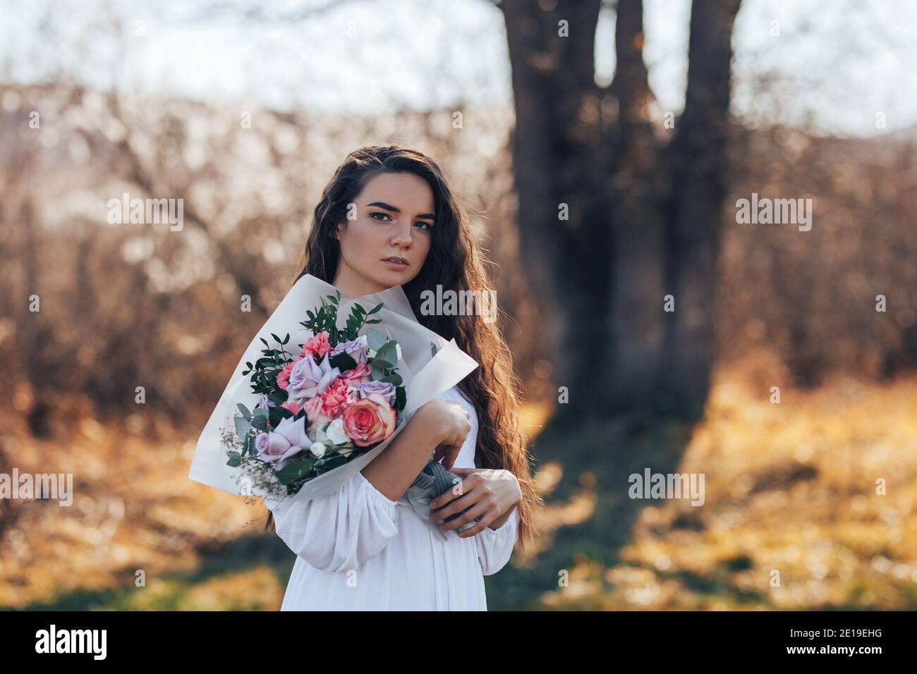 Young woman in white dress holding a beautiful bouquet of roses Stock ...