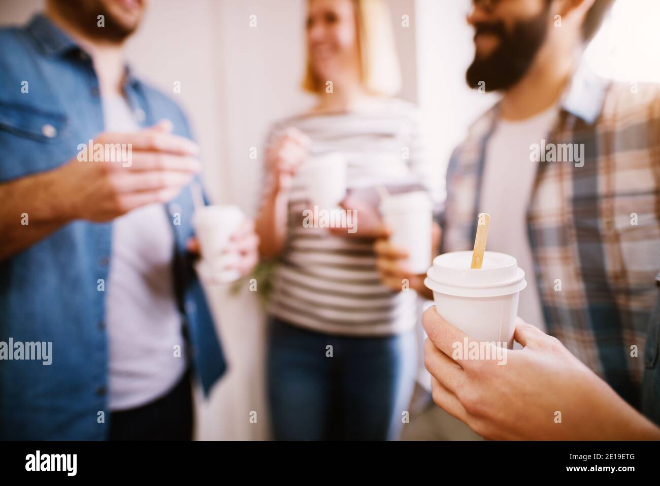 Group of young business people talking to each other and holding paper ...