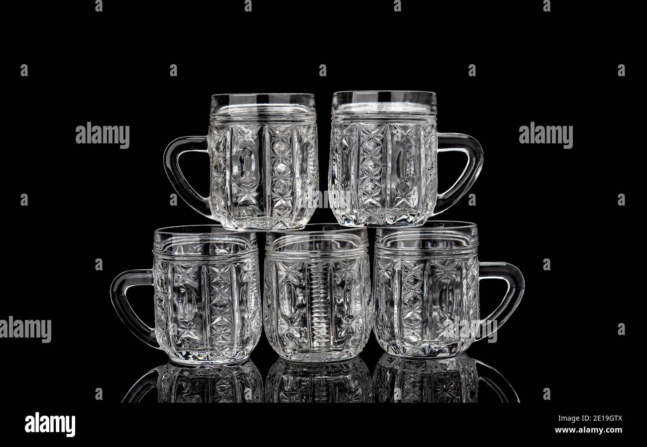 Pyramid of five empty crystal mugs on a black background with