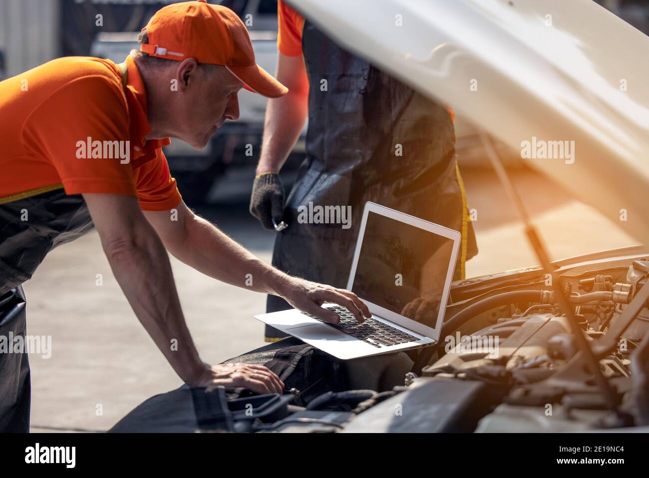 Car maintenance service, technician diagnose car engine failure problem by laptop computer. Stock Photo