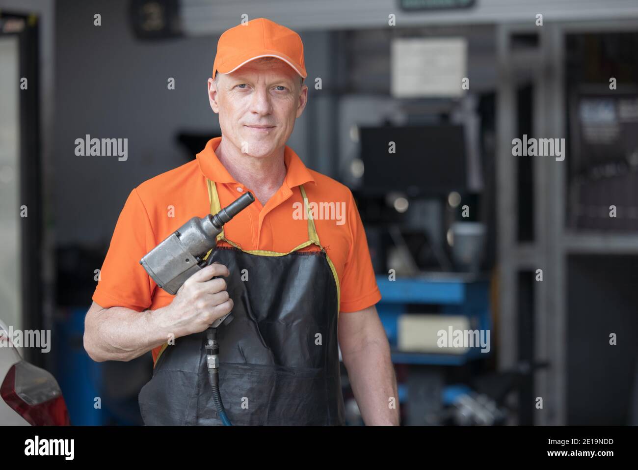 Mechanic Servicing Car Tire With Impact Gun in garage of repair service