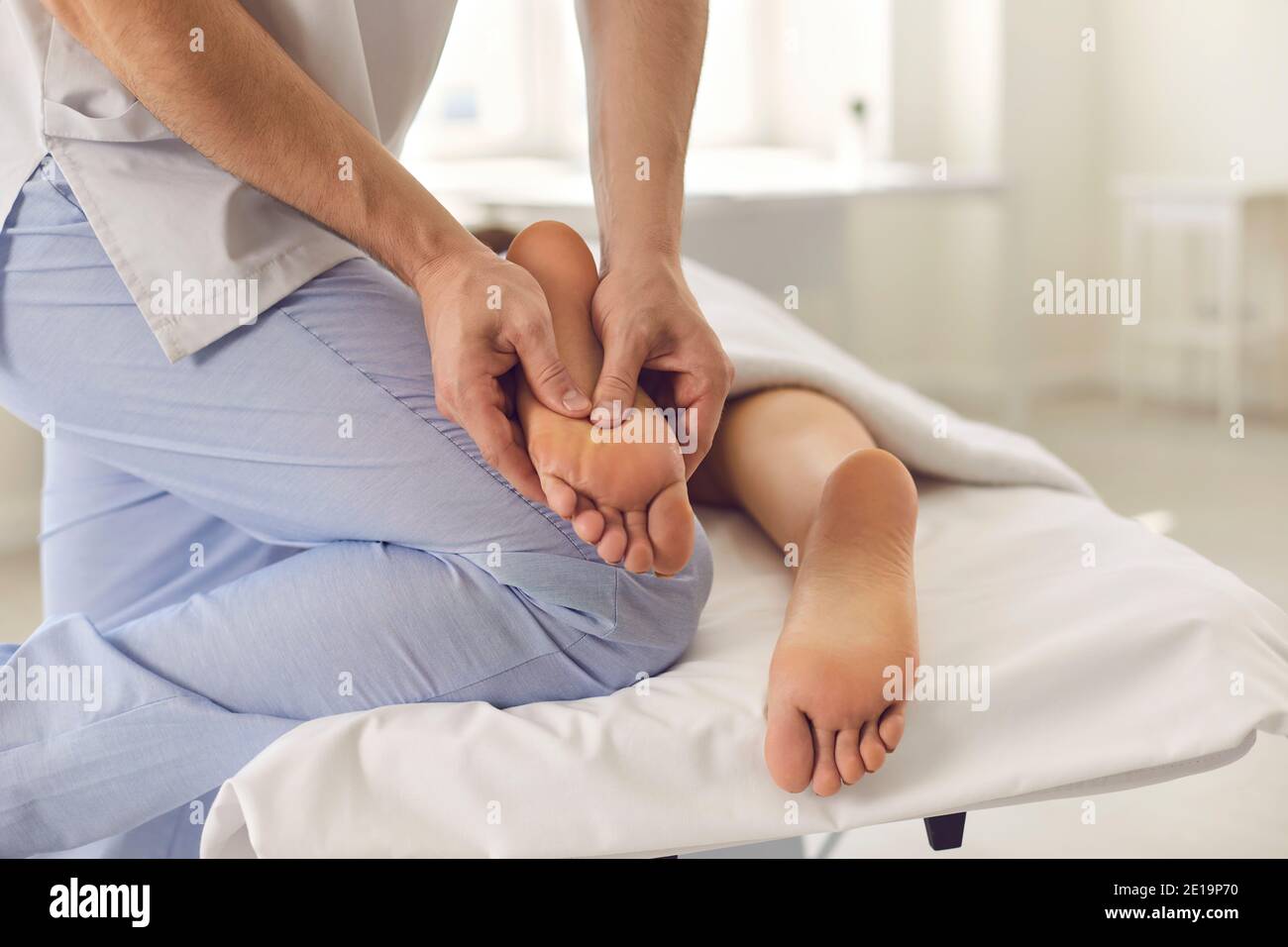 Hands of therapist doing treatment of acupressure or manual massage for patients feet Stock Photo