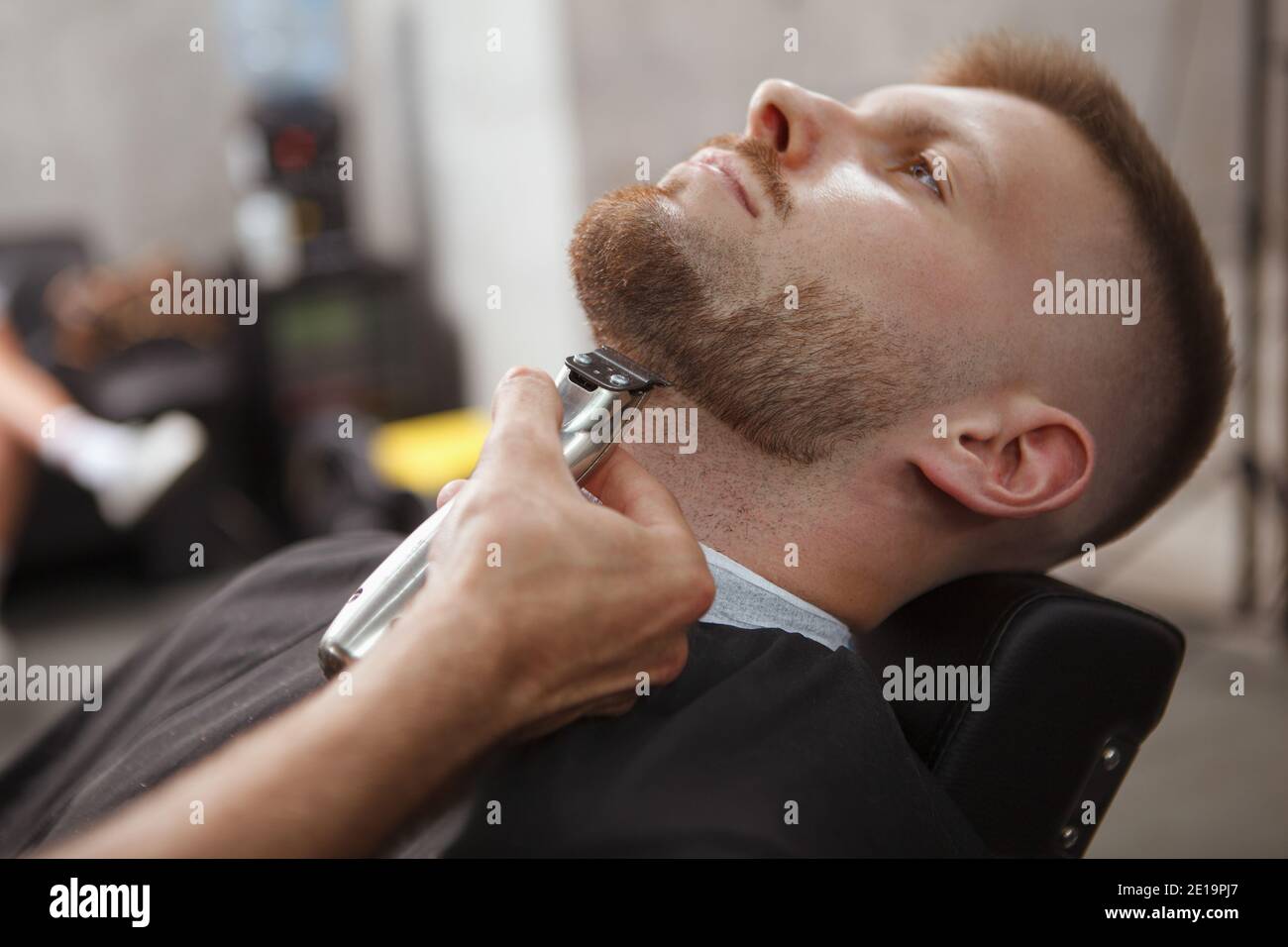 Close up of a young man having his beard trimmed by professional barber