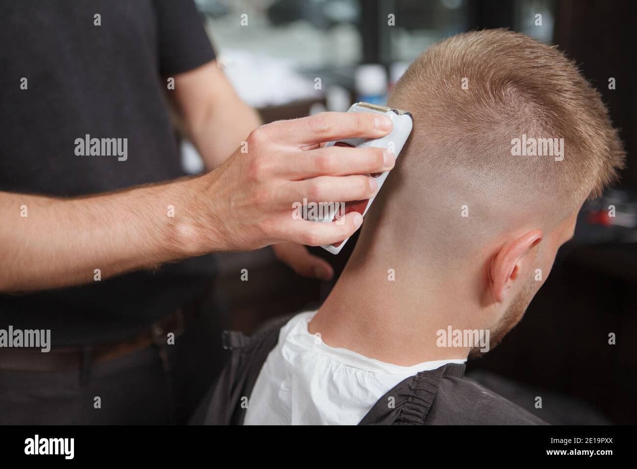 Rear view close up of a barber shaving back of the head of his client Stock Photo