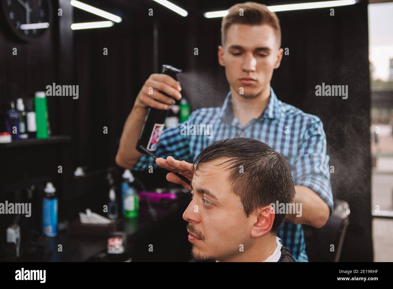 Mature man getting his hair wet by professional barber. Hairstylist spraying hair of a male client with water, copy space. Haircut, hair styling conce Stock Photo