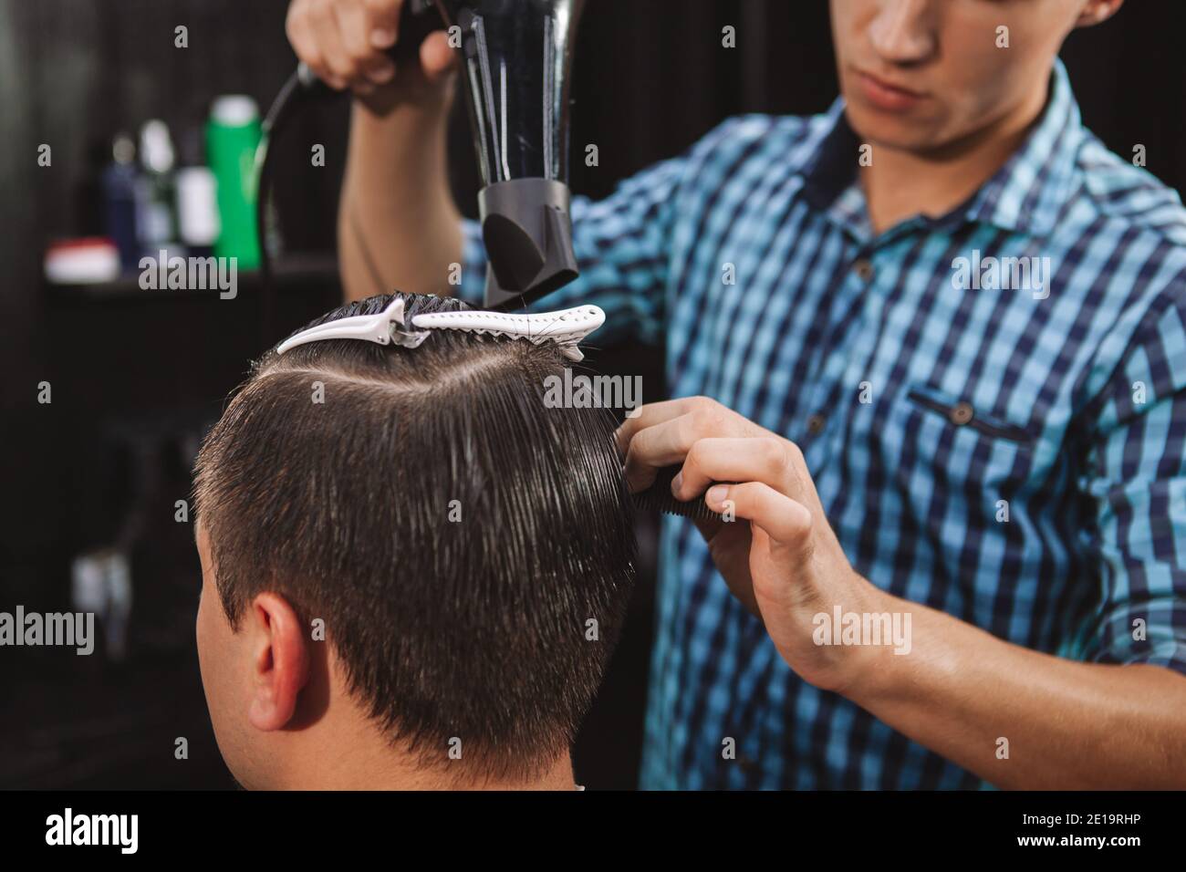 Cropped shot of unrecognizable man getting his hair blow dried by professional barber. Young male hairstylist blow drying hair of a male customer Stock Photo