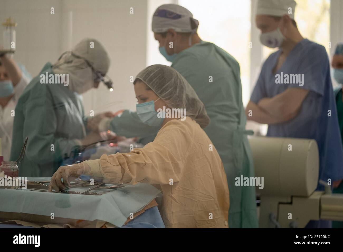 Doctors and nurses perform an operation in an operating room. Team of medical workers wearing face masks and uniforms. City Hospital. May, 2020 Stock Photo