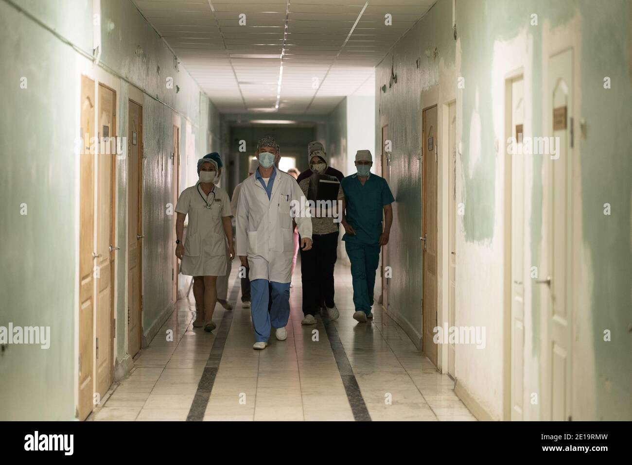 Walking along the hospital corridor group of doctors and nurses. A team of medical workers in uniforms walking along hall. City Hospital. May, 2020 Stock Photo