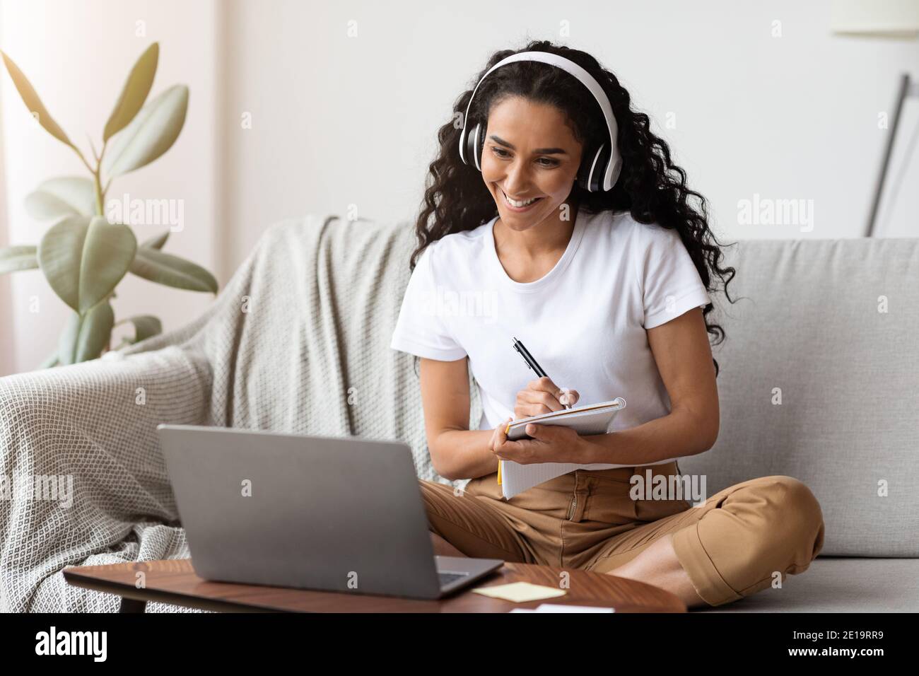 Cheerful lady attending webinar, using laptop and wireless headset Stock Photo