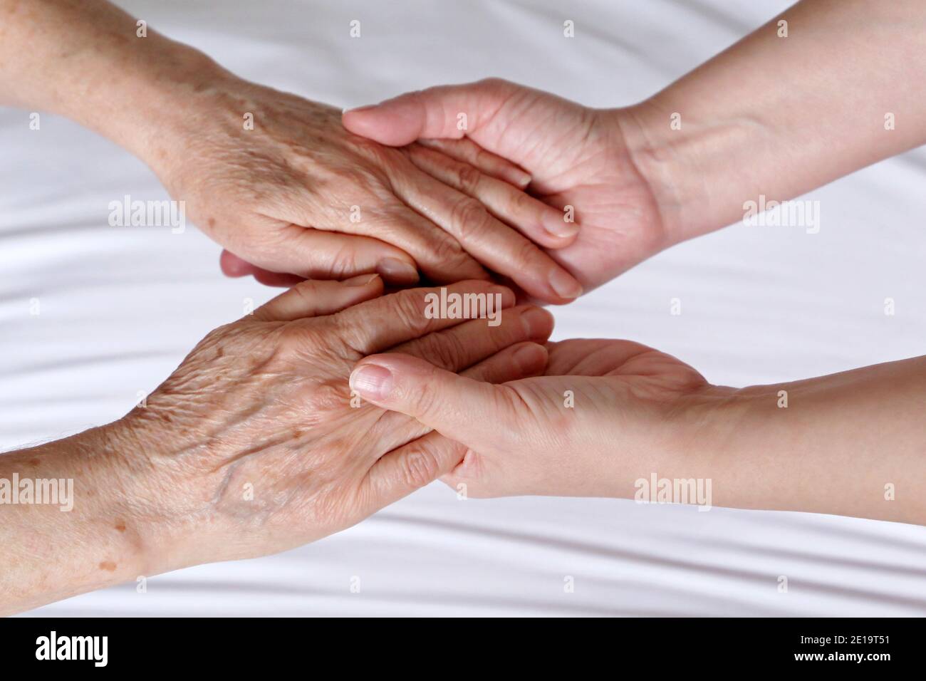 Wrinkled hands of senior woman in the palms of a young woman. Concept of care and support, elderly mother and daughter Stock Photo