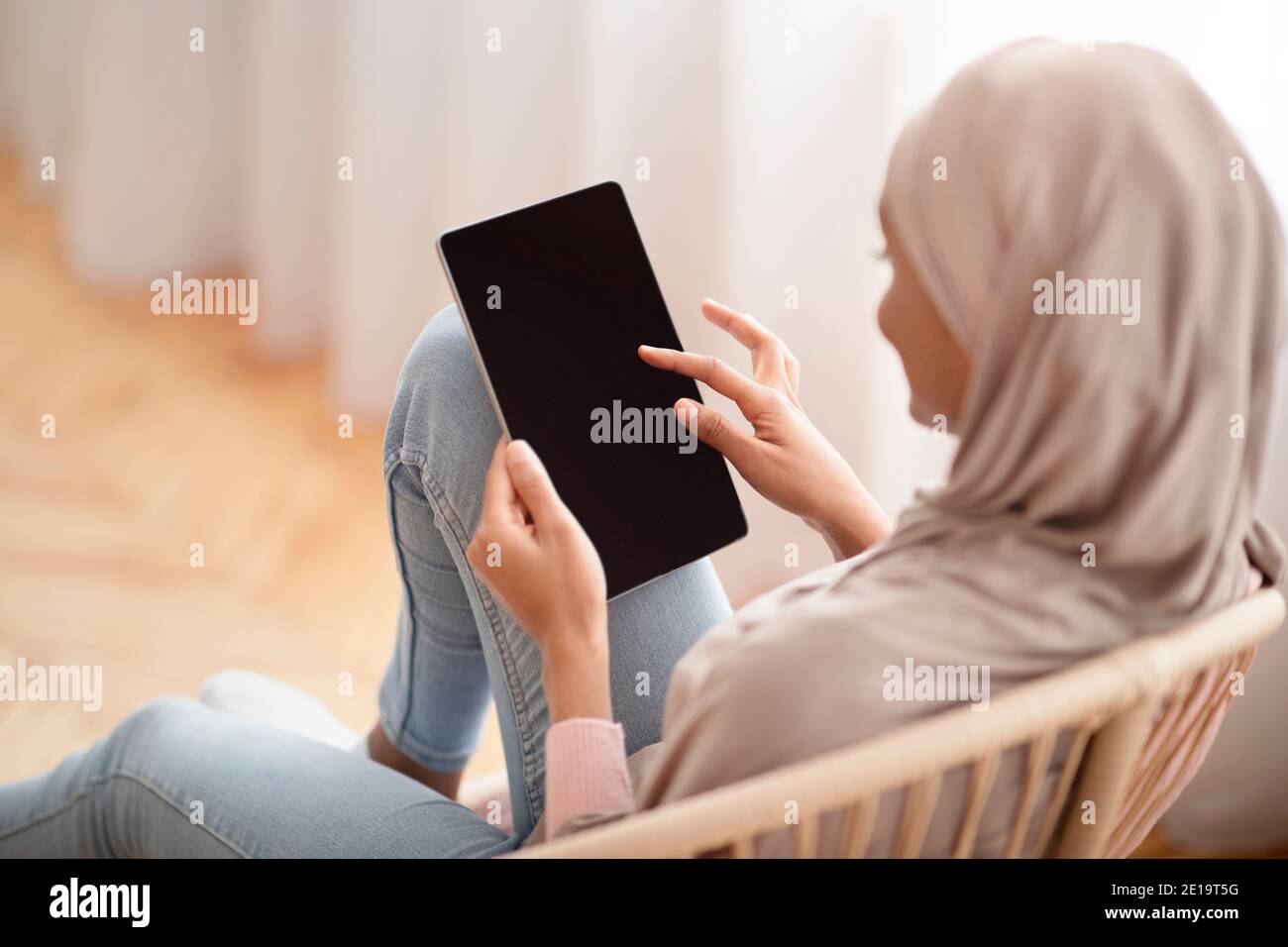 Download Black Arab Woman In Hijab Using Tablet With Empty Screen While Sitting In Cozy Armchair At Home Mockup For Design Stock Photo Alamy