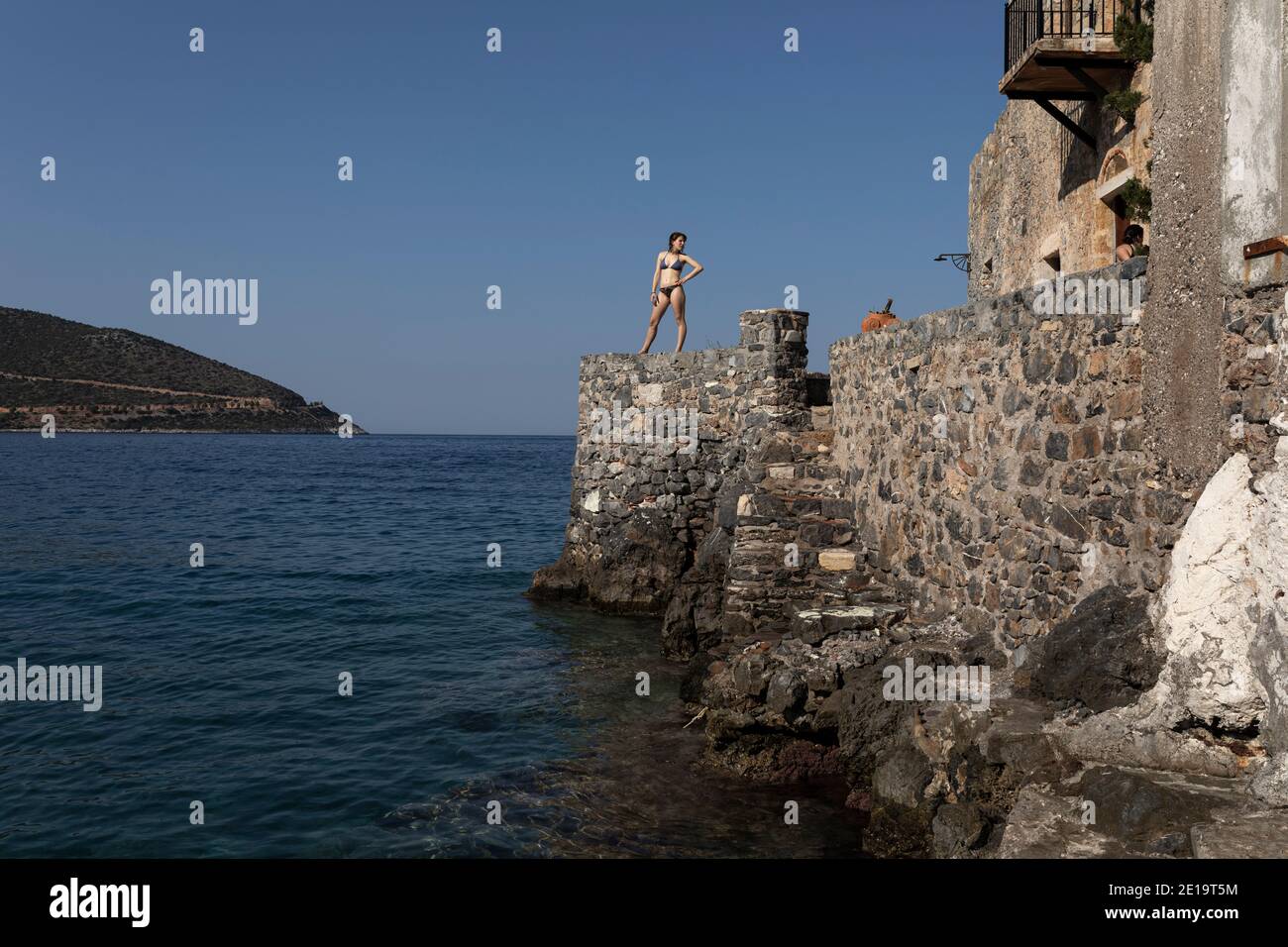 A girl stands by the sea at the port of Kiparissi village, Peloponnese region, Greece on July 28, 2020. / Ενα κορίτσι στέκεται στην προβλήτα του λιμαν Stock Photo