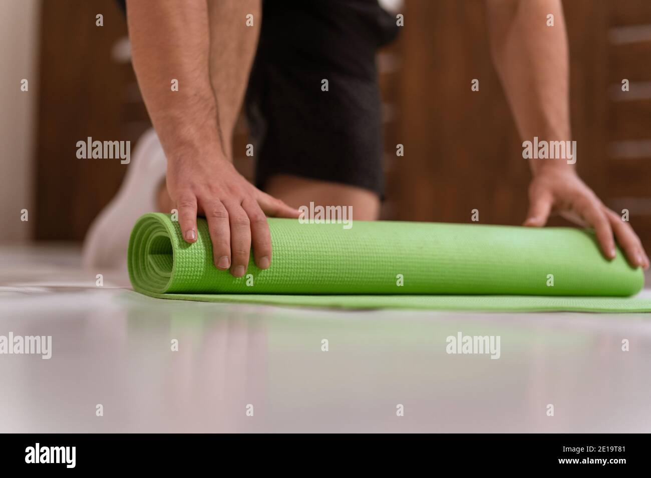 Unwinding roll mat, preparing a place for sports fitness man. Determined guy doing physical training. Strong handsome young man, an a gym Stock Photo