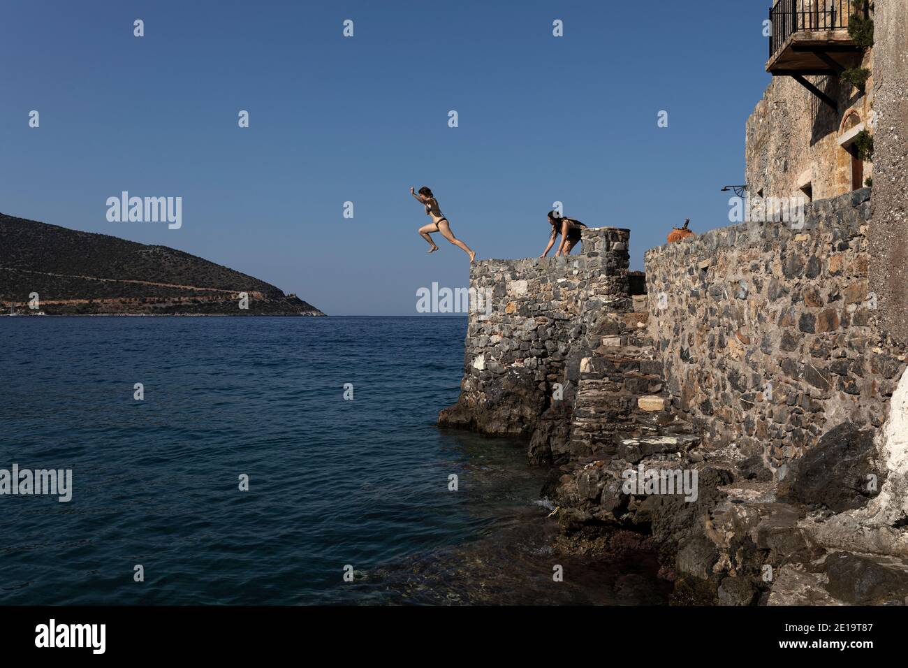 A girl jumps into the sea at the port of Kiparissi village, Peloponnese region, Greece on July 28, 2020. Stock Photo