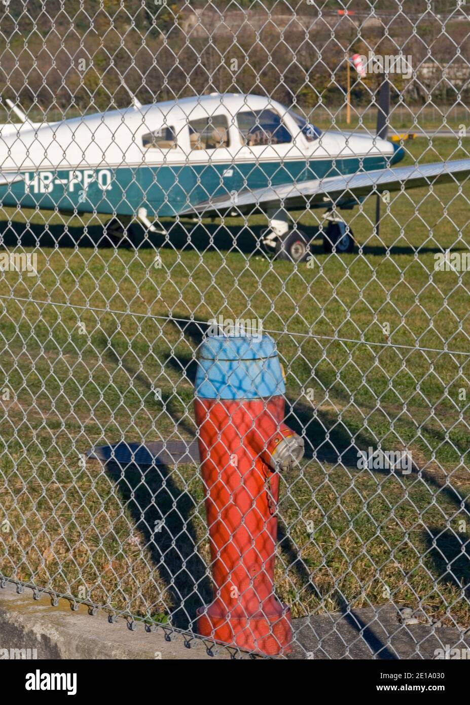 cessna  airplane and hydrant behind an airport fencing net in Lugano, Switzerland Stock Photo