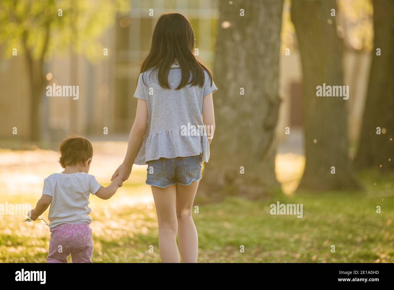 Longueuil, Canada - August 15 2020: Sisters hand in hand walking in the forest in a summer afternoon Stock Photo