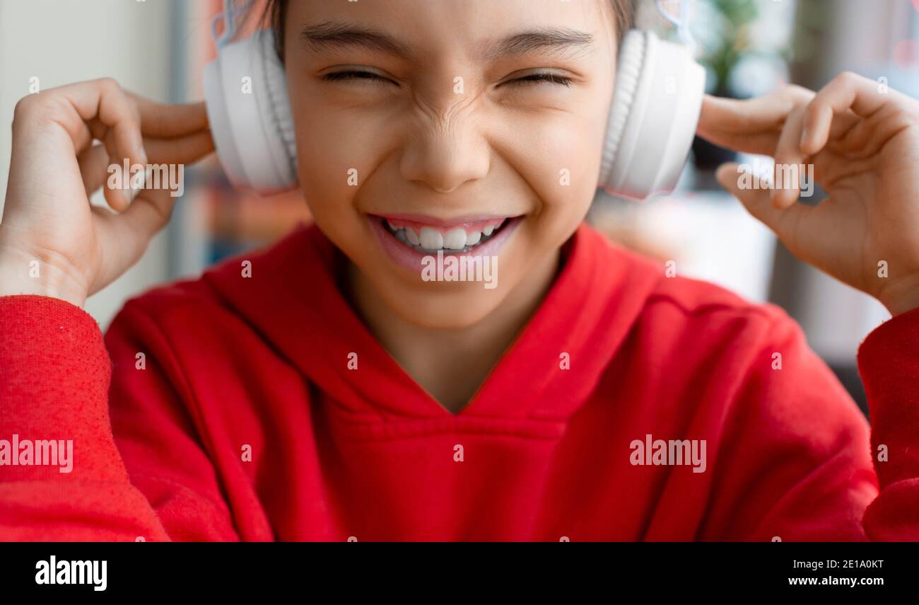 The girl in headphones smiles funny and wrinkles her nose. Modern