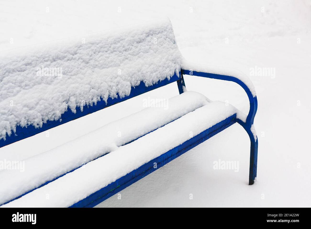 Snowy winter. Blue bench covered with fresh layer of white snow ...