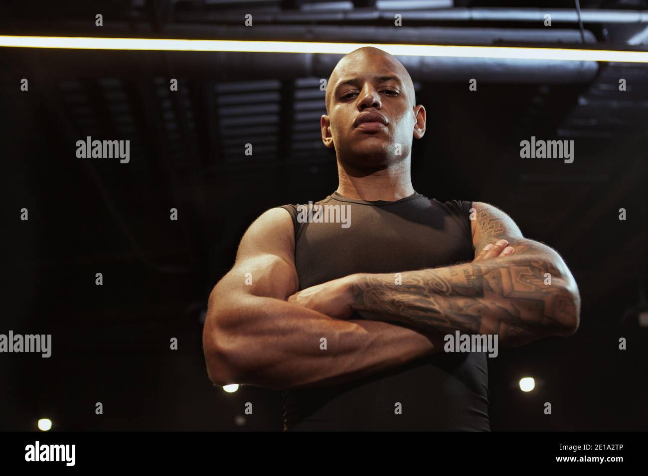 Low angle shot of a handsome African male sportsman looking confidently to  the camera with arms crossed. Fierce muscular athletic man at the gym Stock  Photo - Alamy