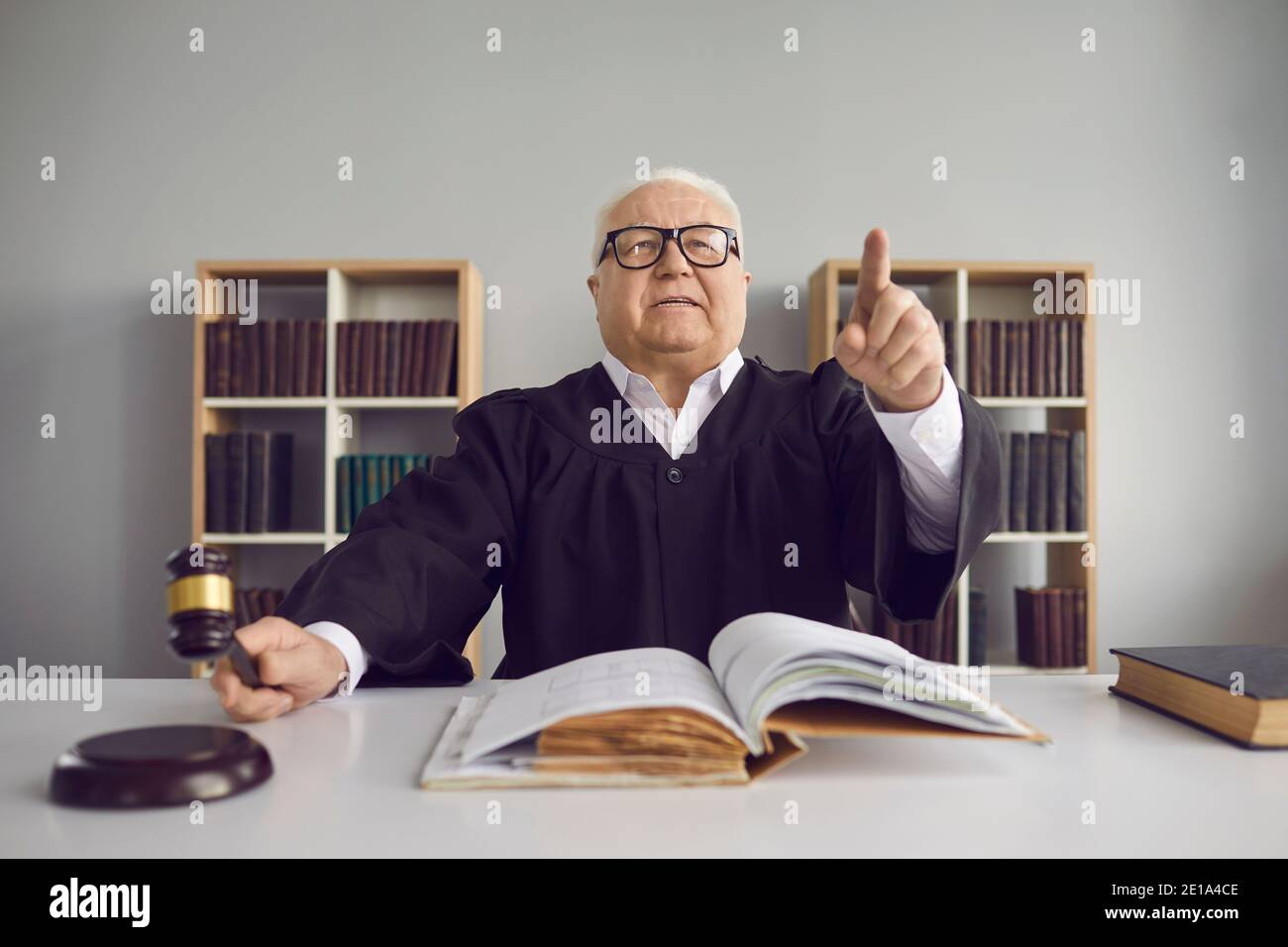 Strict judge hitting sound block with gavel and pronouncing sentence in court hearing Stock Photo