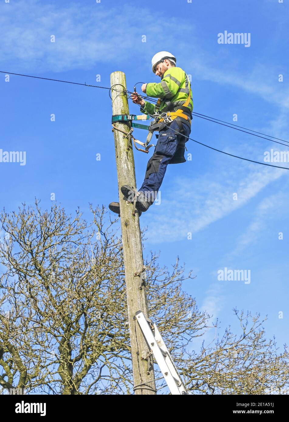 A BT telephone engineer up a pole looking at the wiring, Talke, Stoke
