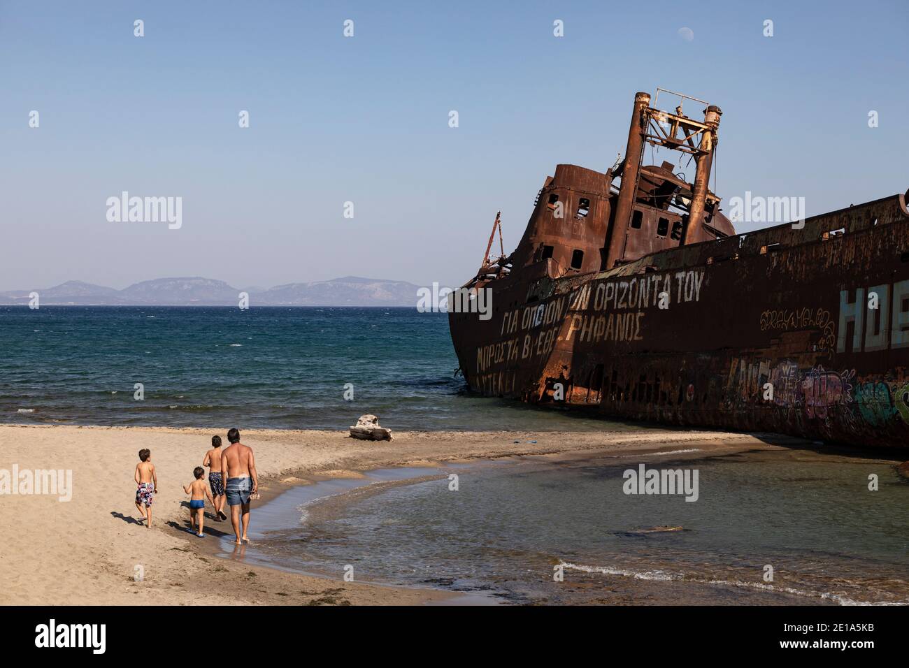 Tourists walk next to the shipwreck «Dimitrios» in Gytheio, Peloponnese region, Greece on July 29, 2020. / Τουρίστες στο ναυάγιο «Δημήτριος», Γύθειο, Stock Photo