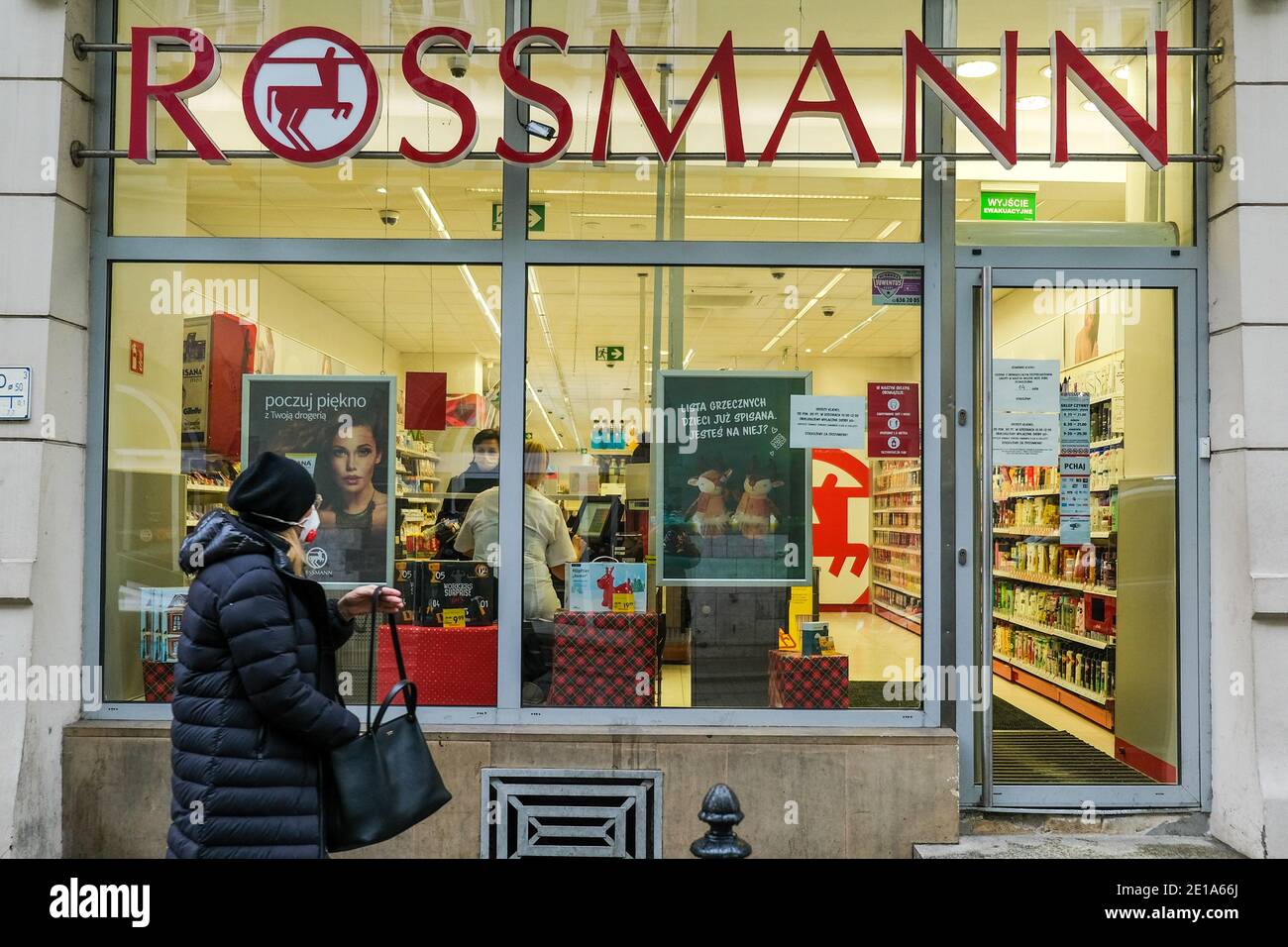 A woman wearing a mask as a preventive measure against the spread of  covid-19 walks past a Rossmann store.Poland is now passing for the second  wave of Coronavirus and life continues under