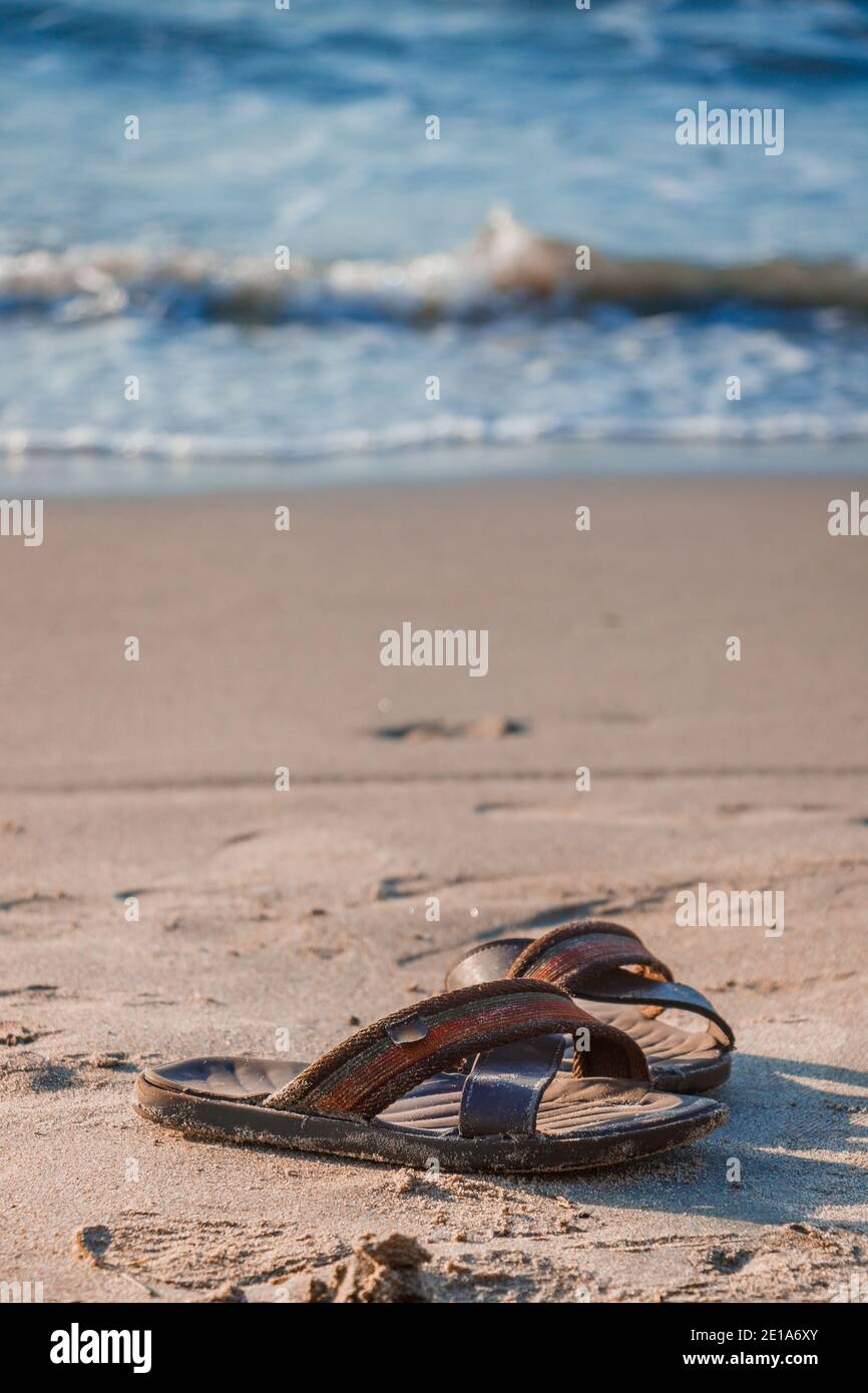 A pair of sandals or flip flops left by its traveler owner on the beach sand while take a dip on the peaceful waters of lonely beach, this is the kinf Stock Photo