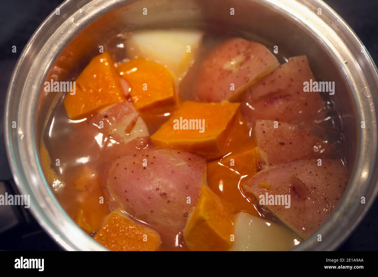 Boiled red potatoes and yams in a stainless steel cooking pot Stock