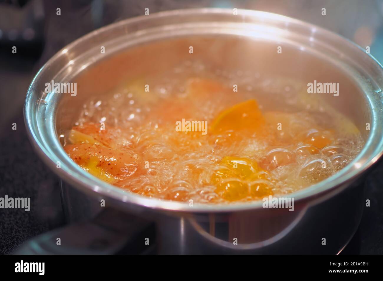 Boiling potatoes and yams in a stainless steel cooking pot with steam