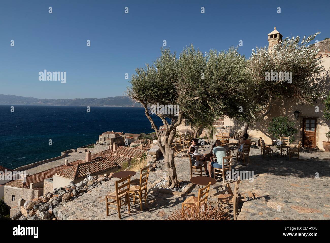 A tourist family enjoy their breakfast at a coffee shop in the castle city of Monemvasia island, Peloponnese region, Greece on July 29, 2020. / Τουρίσ Stock Photo