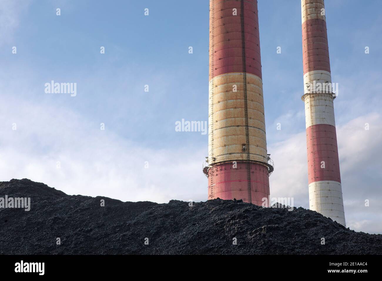Coal heap, natural black coal with industrial chimneys. Industrial background. Global warming, CO2 emission, coal energy issues, energy from fossil fu Stock Photo
