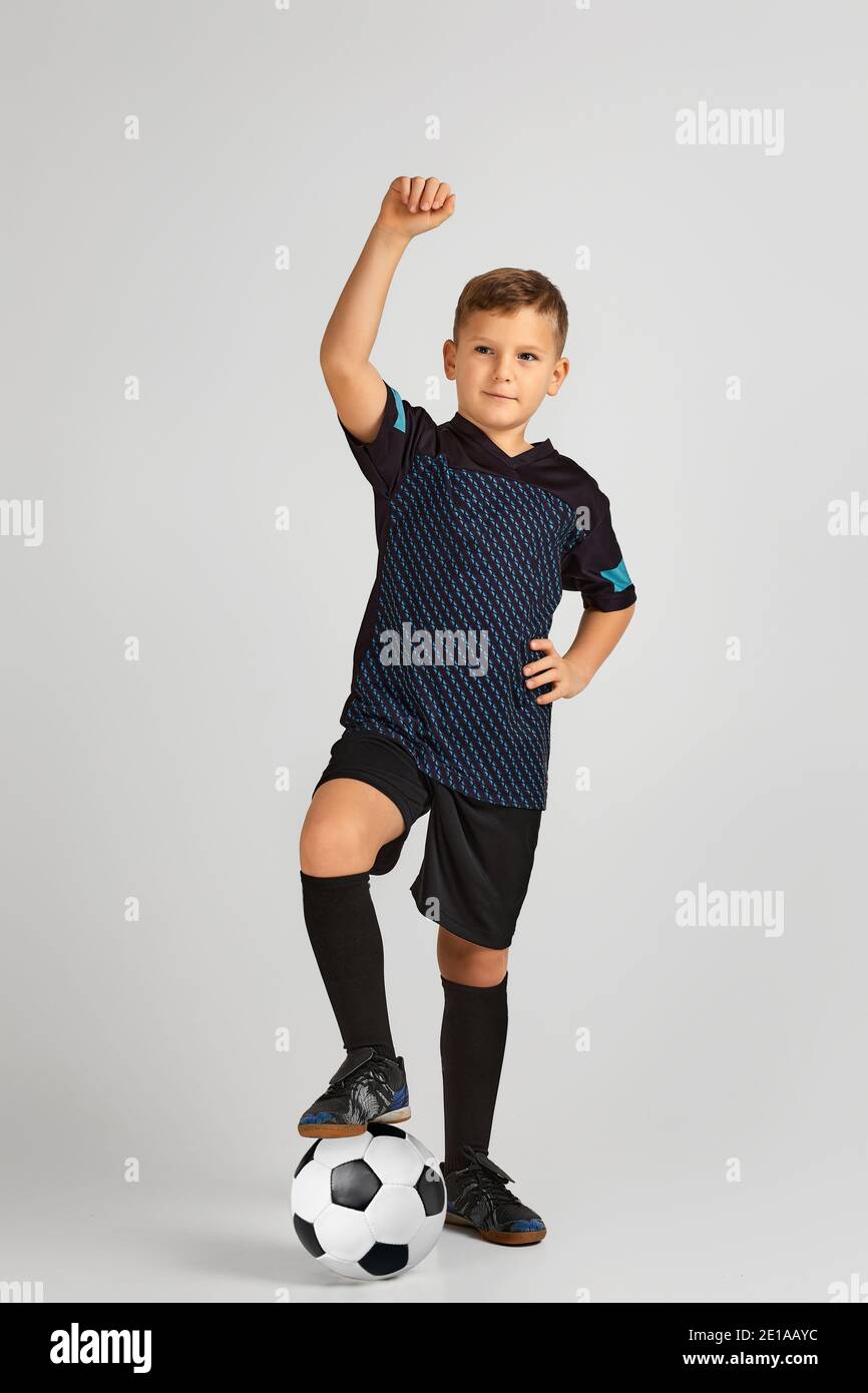 little-boy-football-player-in-uniform-holding-his-leg-on-ball-over