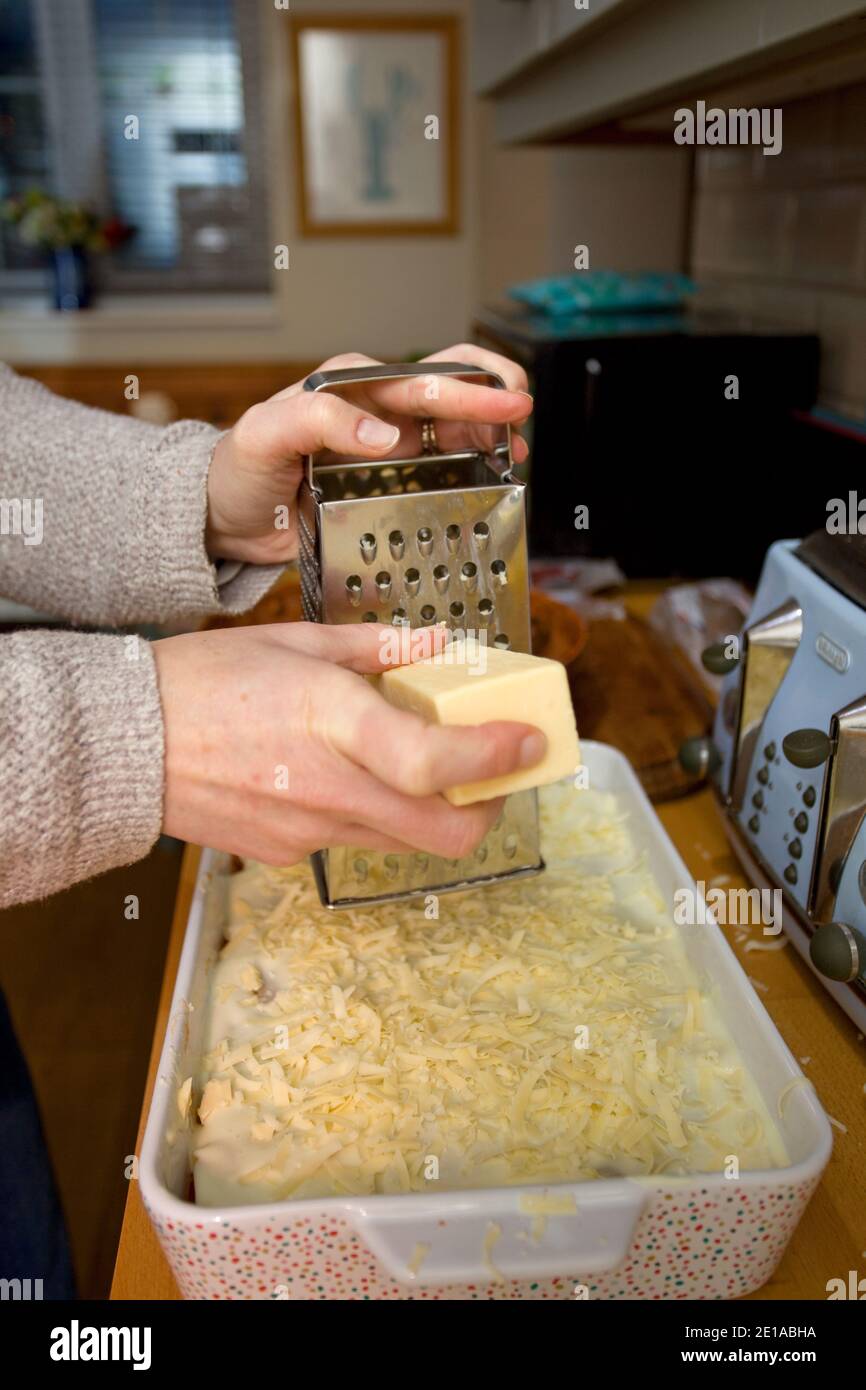 Grating cheddar cheese on top of lasagna dish Stock Photo Alamy