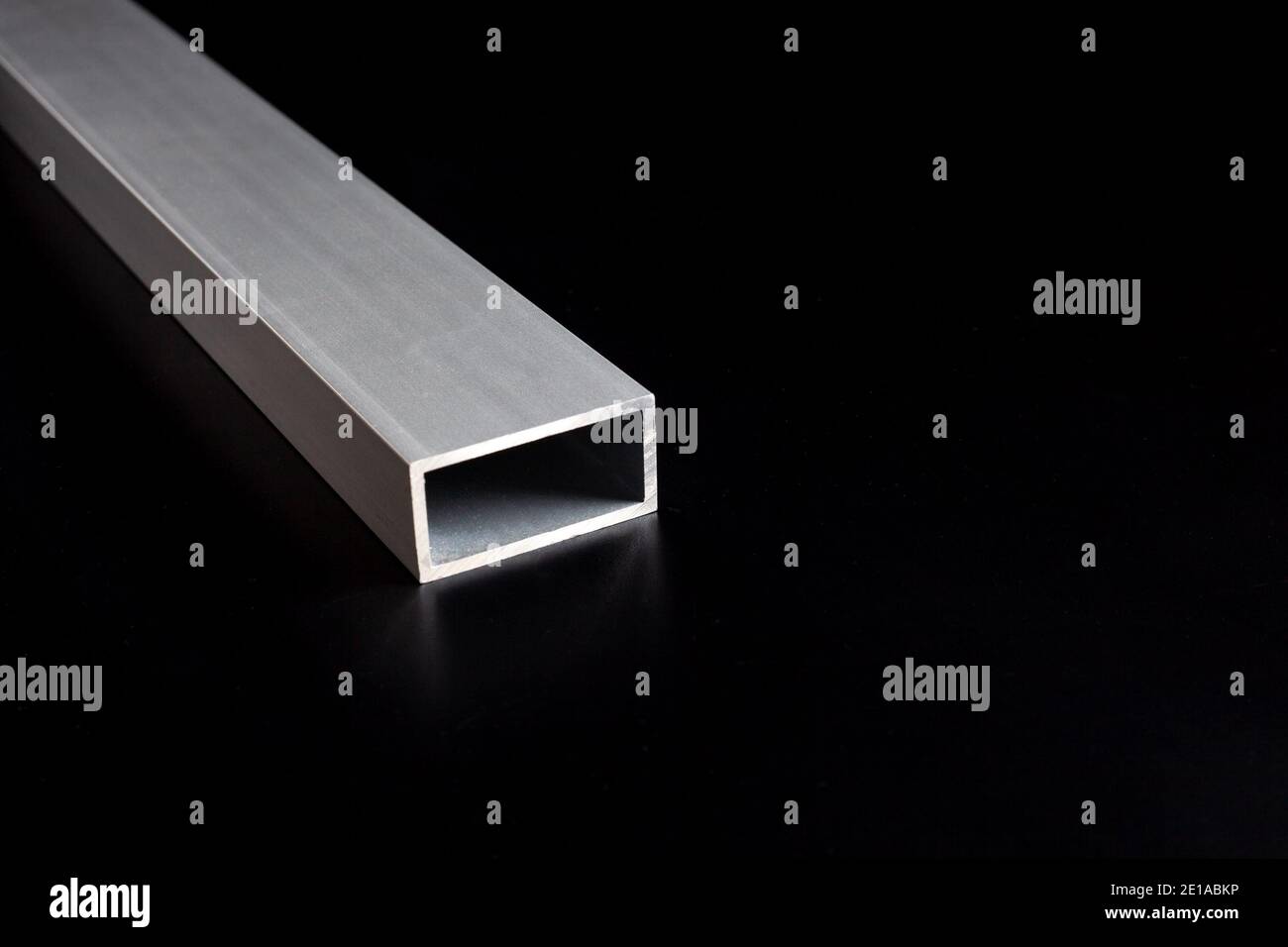 Photo of aluminium steel tube profile for windows and doors manufacturing. Aluminium constructions on dark surface background. Stock Photo