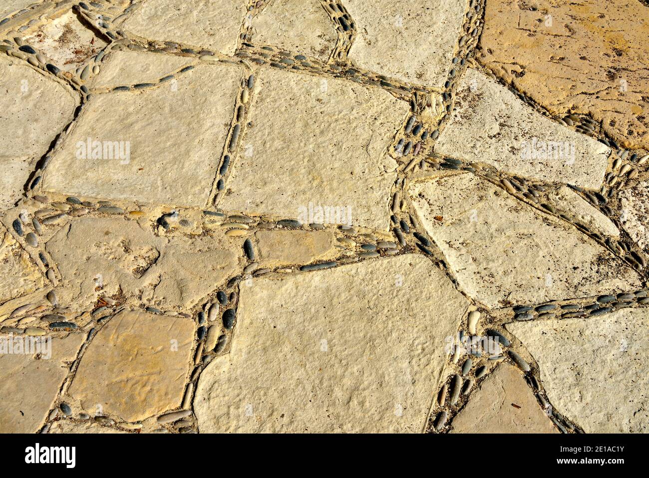 Stone “crazy paving” pavement with small pebbles between the larger stones by beach Stock Photo