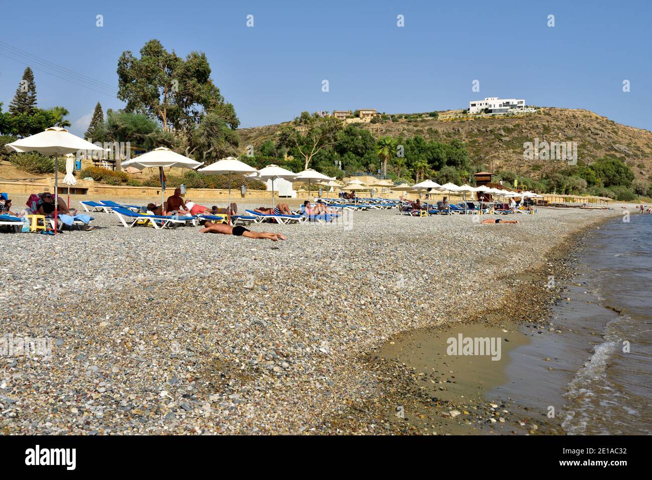 Pissouri pebbly beach with deck chairs and shade umbrellas on Mediterranean sea, Pissouri, Cyprus Stock Photo