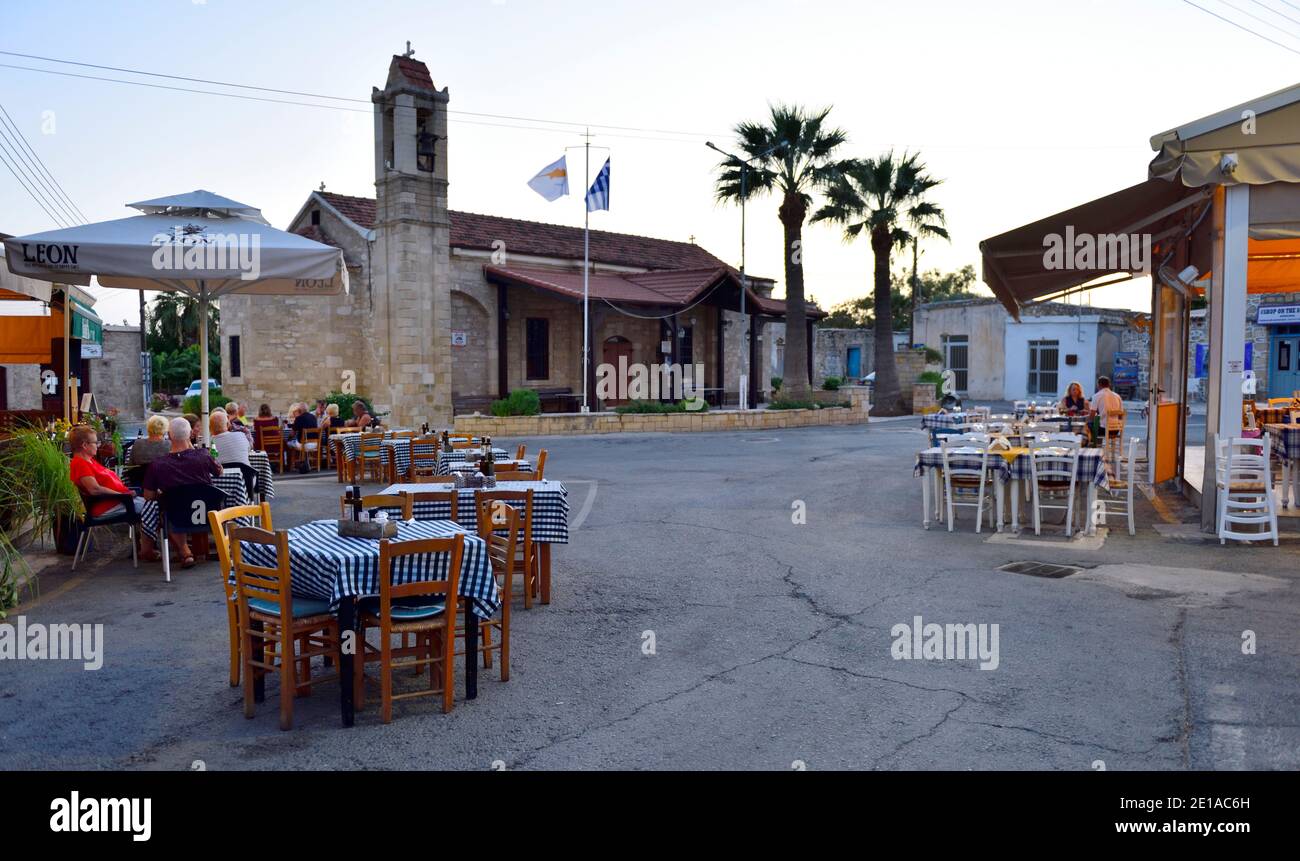 Village central road junction closed to traffic and used by multiple restaurants and taverns outside for dinning. Kouklia, Cyprus Stock Photo