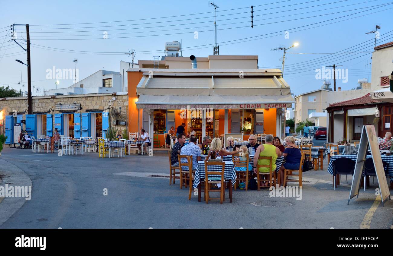 Village central road junction closed to traffic and used by multiple restaurants and taverns outside for dinning. Kouklia, Cyprus Stock Photo