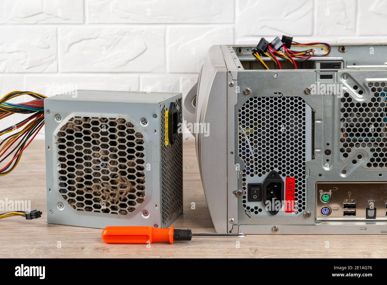 Old faulty power supply unit and a screwdriver near tower case with