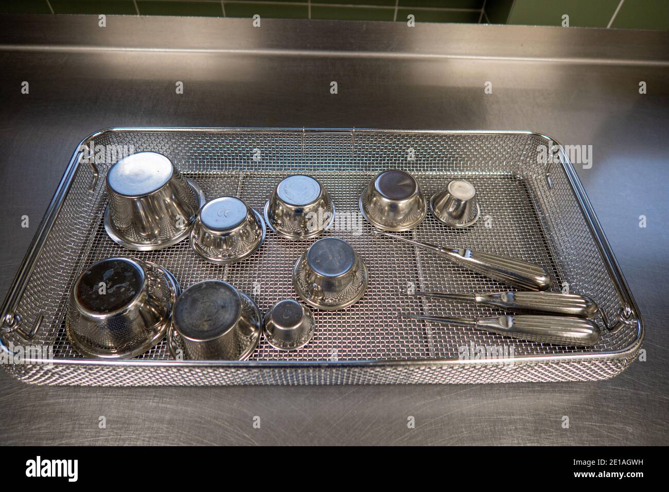 various surgical instruments lie in sieves on a work surface Stock Photo