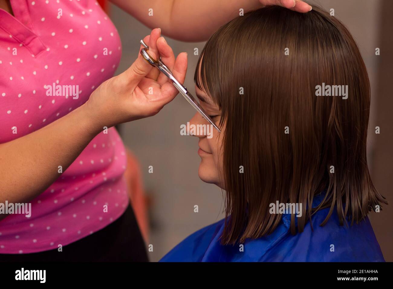 Professional female hairdresser cutting girl's hair in salon Stock