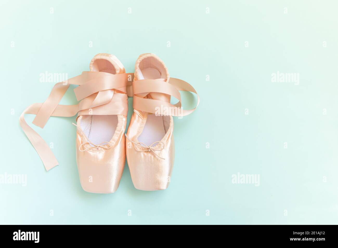 New pastel beige ballet shoes with satin ribbon isolated on blue