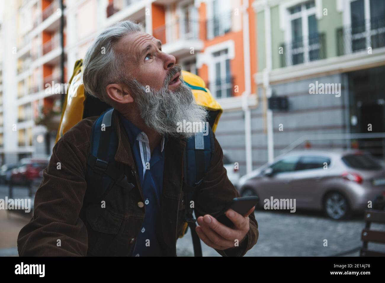 Senior deliveryman riding bicycle, using smart phone to navigate Stock Photo