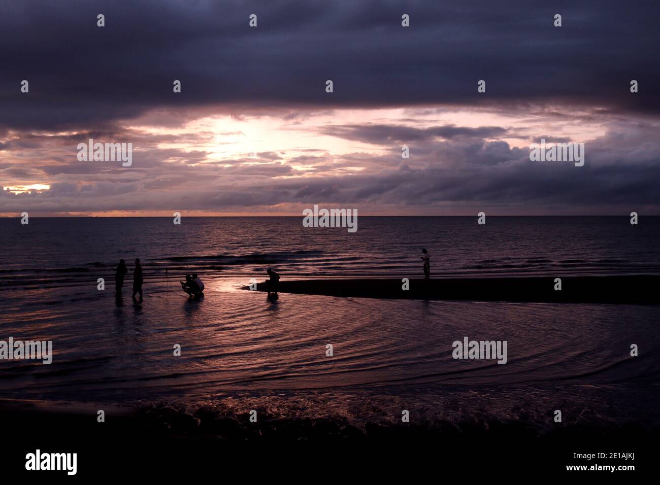 Beach goers taking selfies, groupies at dawn. Stock Photo